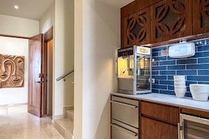 Una cocina con una máquina de palomitas, gabinetes de madera y un respuesto de azulejos azules.
