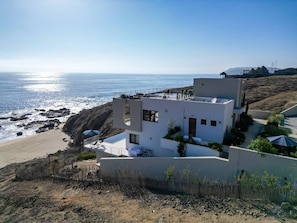 Un edificio moderno frente al mar, con techo plano, ventanas grandes y vistas al océano.