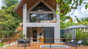 Een modern herenhuis met twee verdiepingen, een houten terras, zitplaatsen buiten en een jacuzzi.