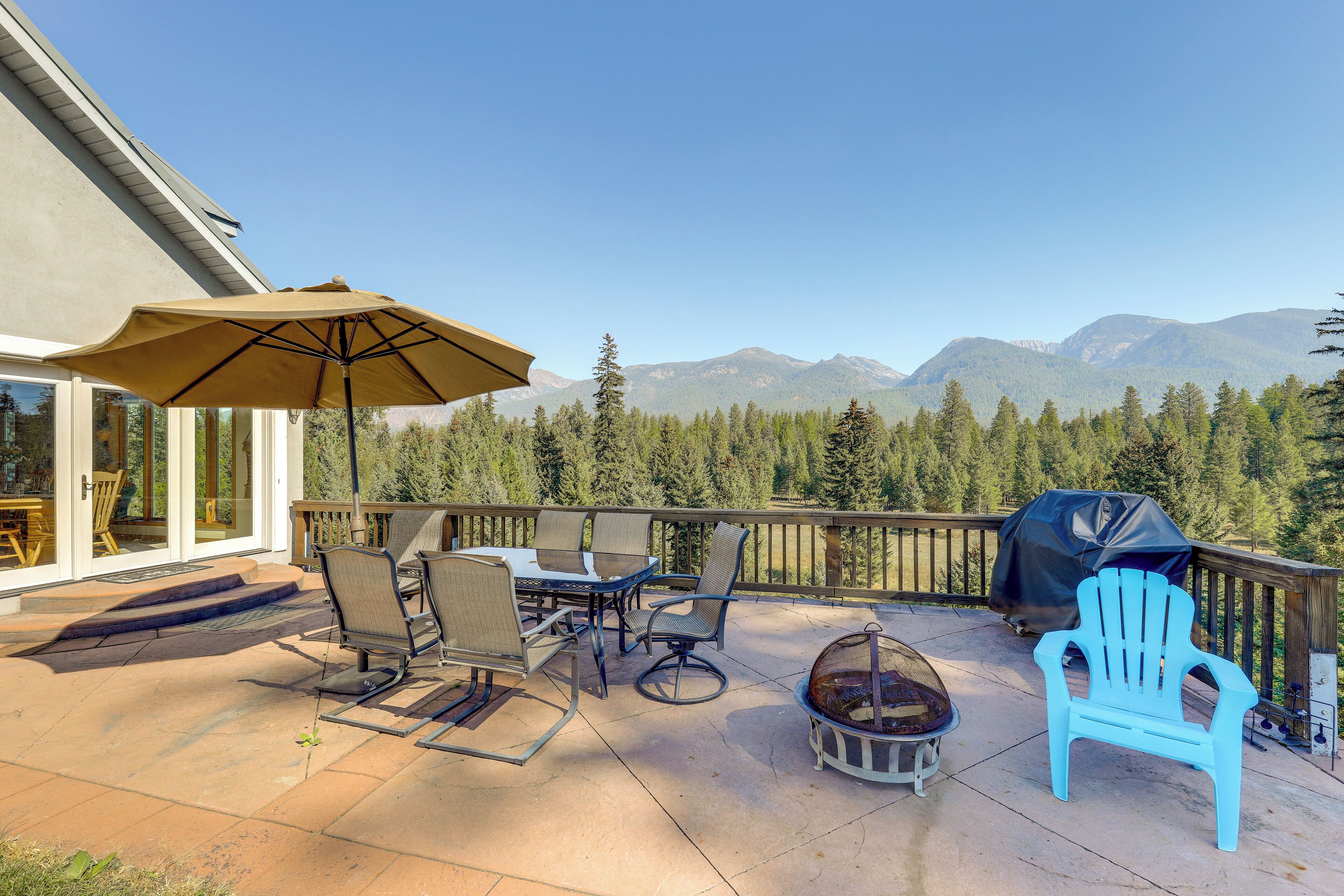 Un patio con mobiliario exterior, una parrilla y una vista panorámica de la montaña.