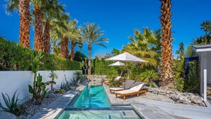 A swimming pool with lounge chairs and umbrellas, surrounded by palm trees and a white wall. - Palm Springs Oasis • 3 King Ensuites + Pool & Spa (Palm Springs)