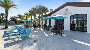 A bar and lounge area with outdoor seating, palm trees, and a building with a sign reading "Tu Casa BAR & LOUNGE". - Family Oasis! Luxe 5BD/4.5BA Townhouse w/Private pool, Disney Proximity (Kissimmee)