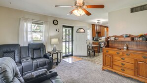 A living room with a leather sofa, a wooden cabinet, and a ceiling fan. - 2 Mi to Zoo, Fenced Yard: Family Home in Wichita! (Wichita)