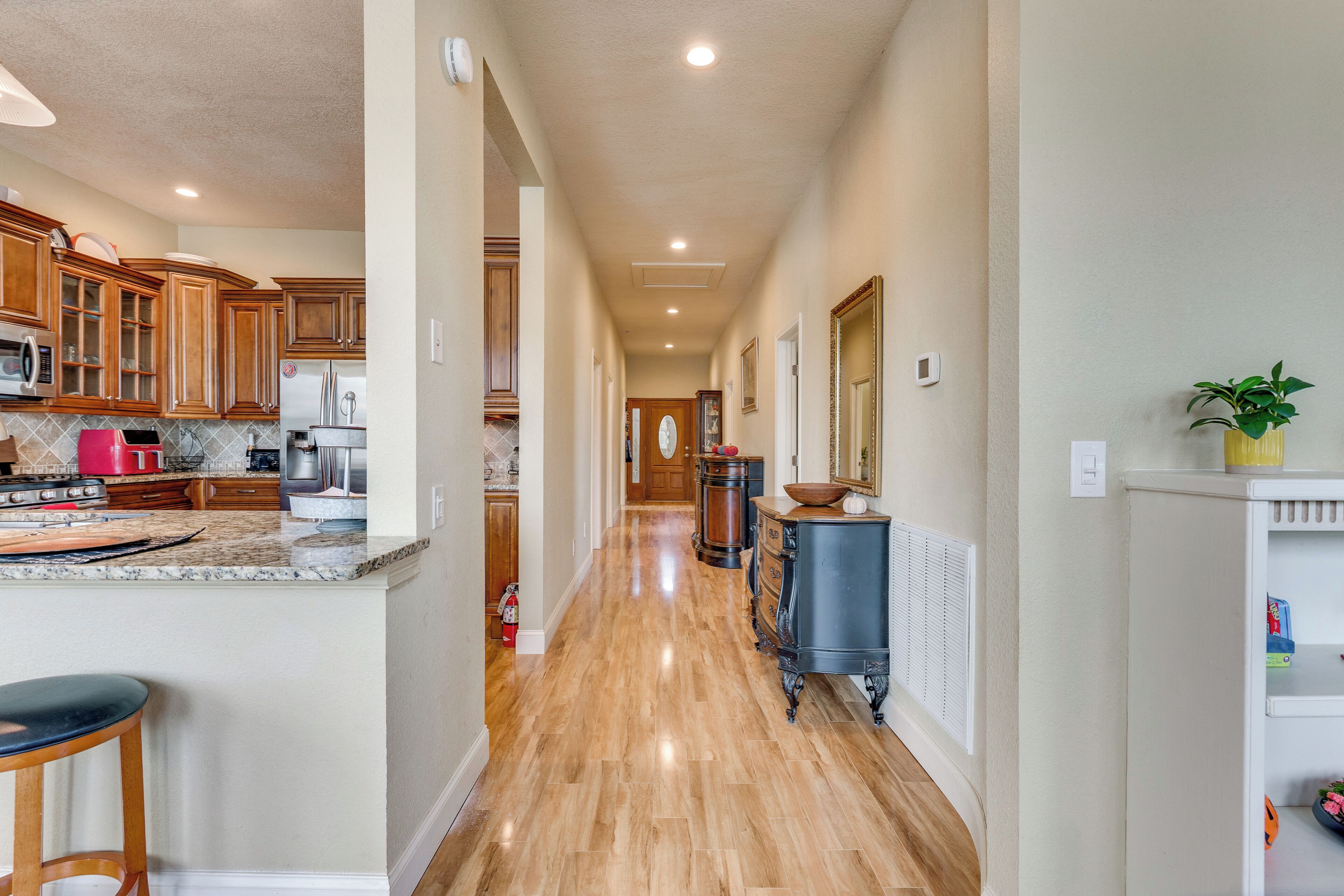 A kitchen with wooden cabinets, a granite countertop, and a stainless steel refrigerator.