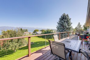 Une terrasse avec une table et des chaises, donnant sur une pelouse verdoyante et une chaîne de montagnes.