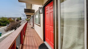 Ein Balkon mit roter Tür, einem Fenster und Blick auf die Straße.