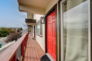 Un balcon avec une porte rouge, une fenêtre et une vue sur la rue.