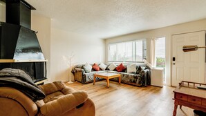 Ein Wohnzimmer mit Sofa, Couchtisch, Kamin und einer Tür.