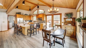 Un'ampia cucina con mobili in legno, un'area pranzo con un tavolo e sedie di grandi dimensioni e un soffitto alto con travi a vista.