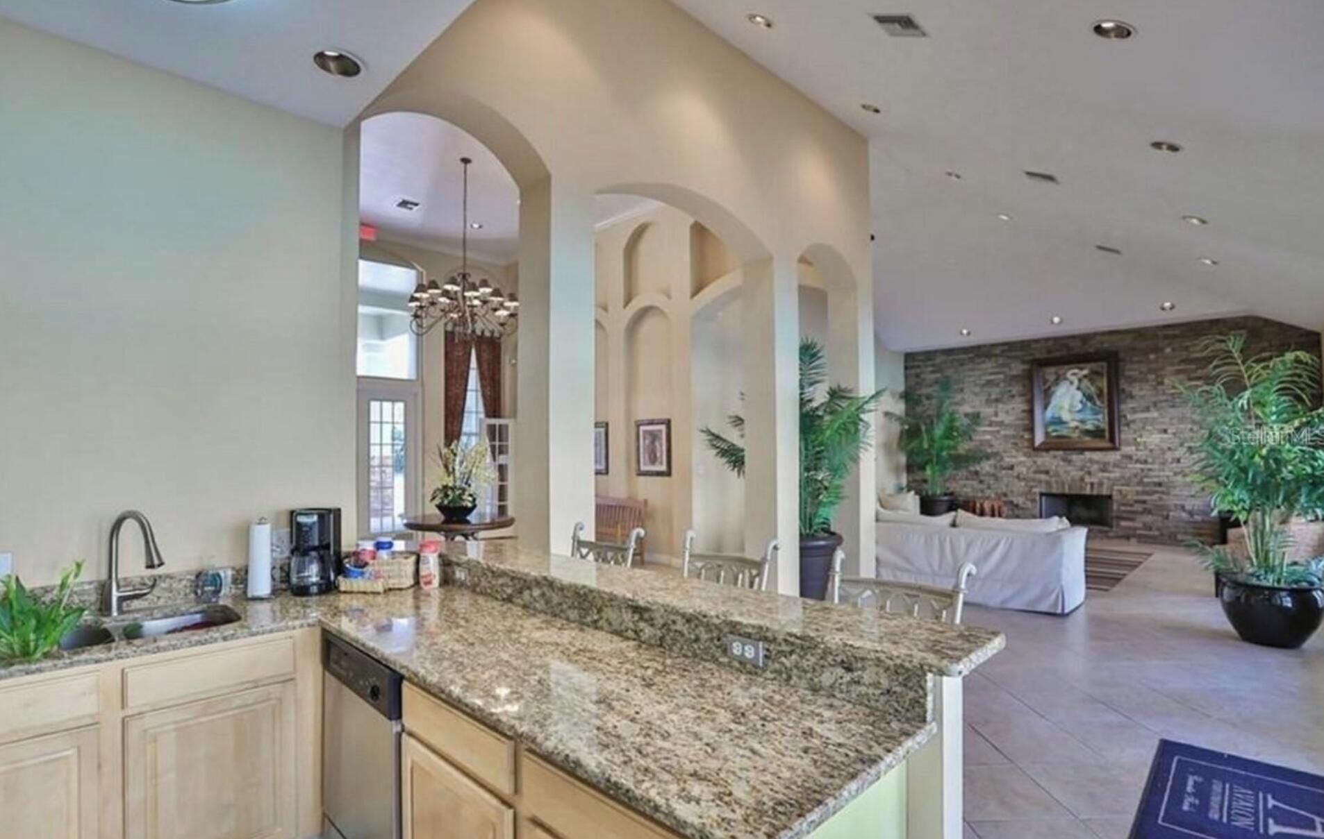 A spacious kitchen with granite countertops, a dishwasher, and a dining area with a stone fireplace.
