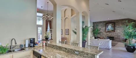 A spacious kitchen with granite countertops, a dishwasher, and a dining area with a stone fireplace.