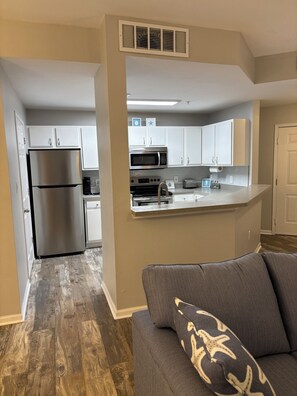 A modern kitchen with white cabinets, a stainless steel refrigerator, a microwave, and a toaster.