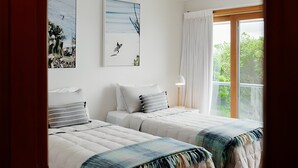Un dormitorio con dos camas, un ventilador de techo, una ventana con cortinas y obras de arte en las paredes.