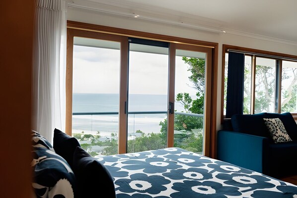 Une chambre avec un grand lit, un canapé bleu et une vue sur la mer.
