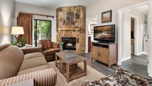A living room with a stone fireplace, a television, and a sofa.