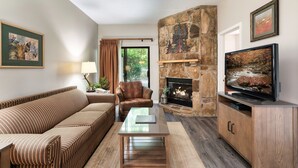 A living room with a stone fireplace, a television, a sofa, and a coffee table.
