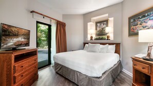 A hotel room with a bed, wooden dresser, television, and artwork on the walls.