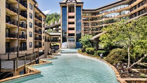 A multi-story hotel with a central water feature, balconies, and lush landscaping.