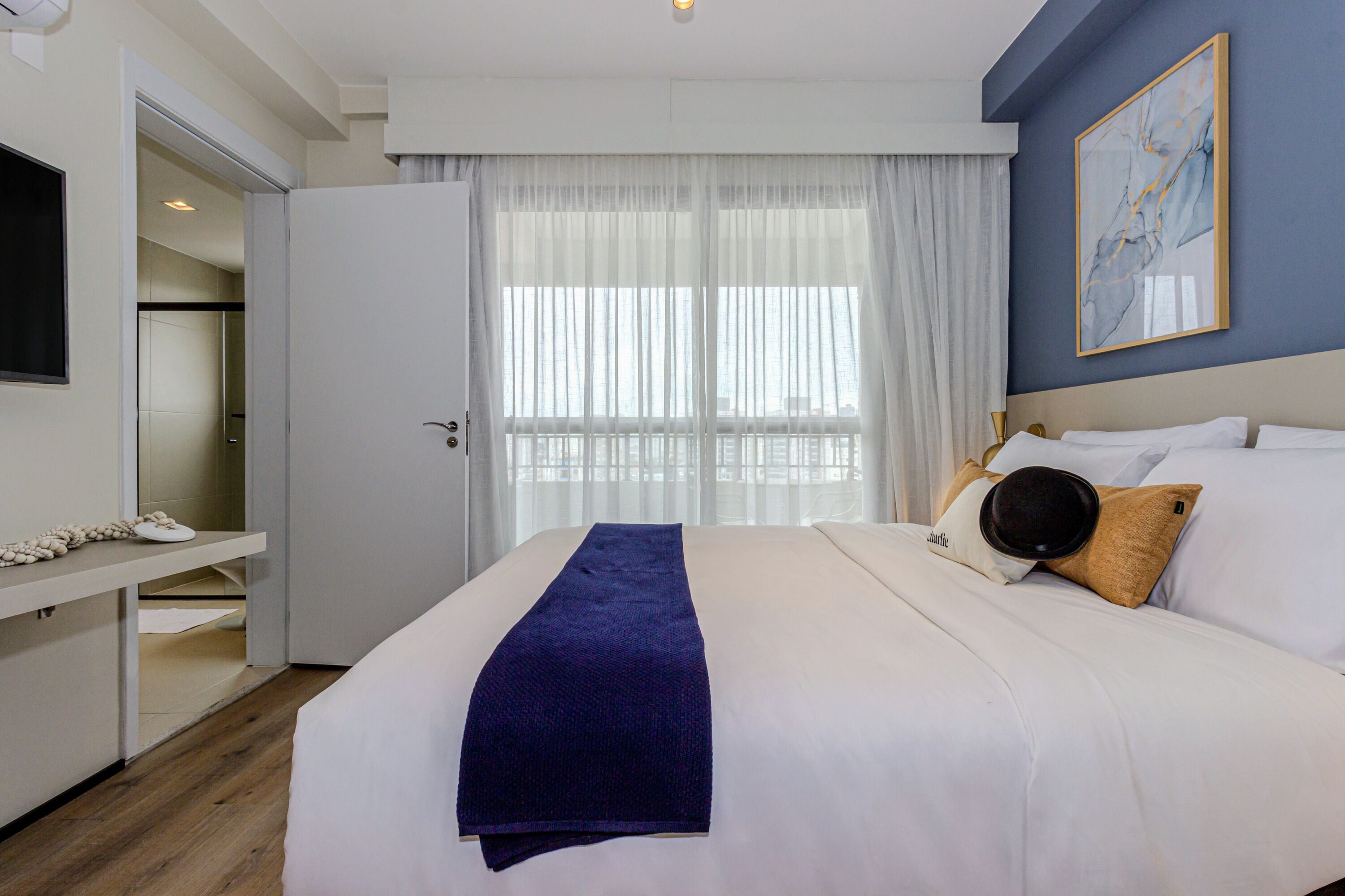 Una habitación de hotel con una cama, una mesita de noche, un televisor y una ventana con cortinas.