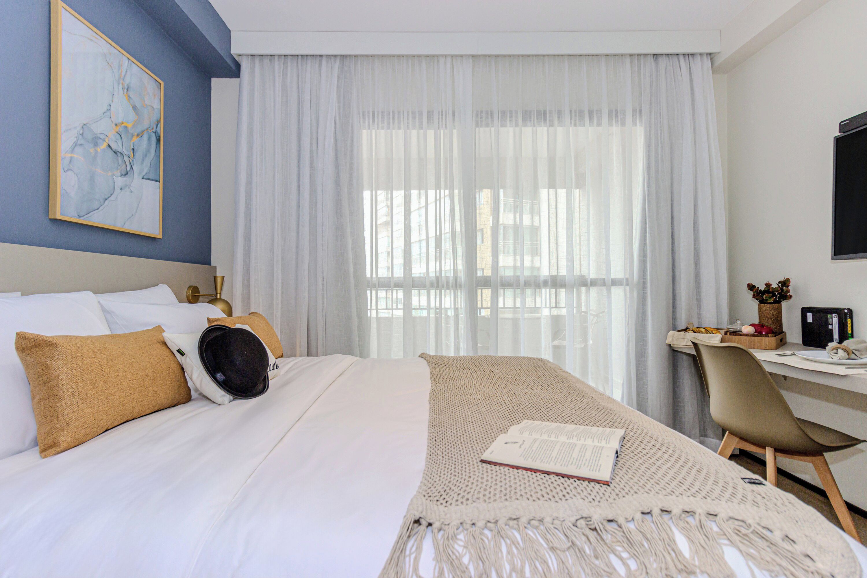 A hotel room with a bed, a desk, and a chair.