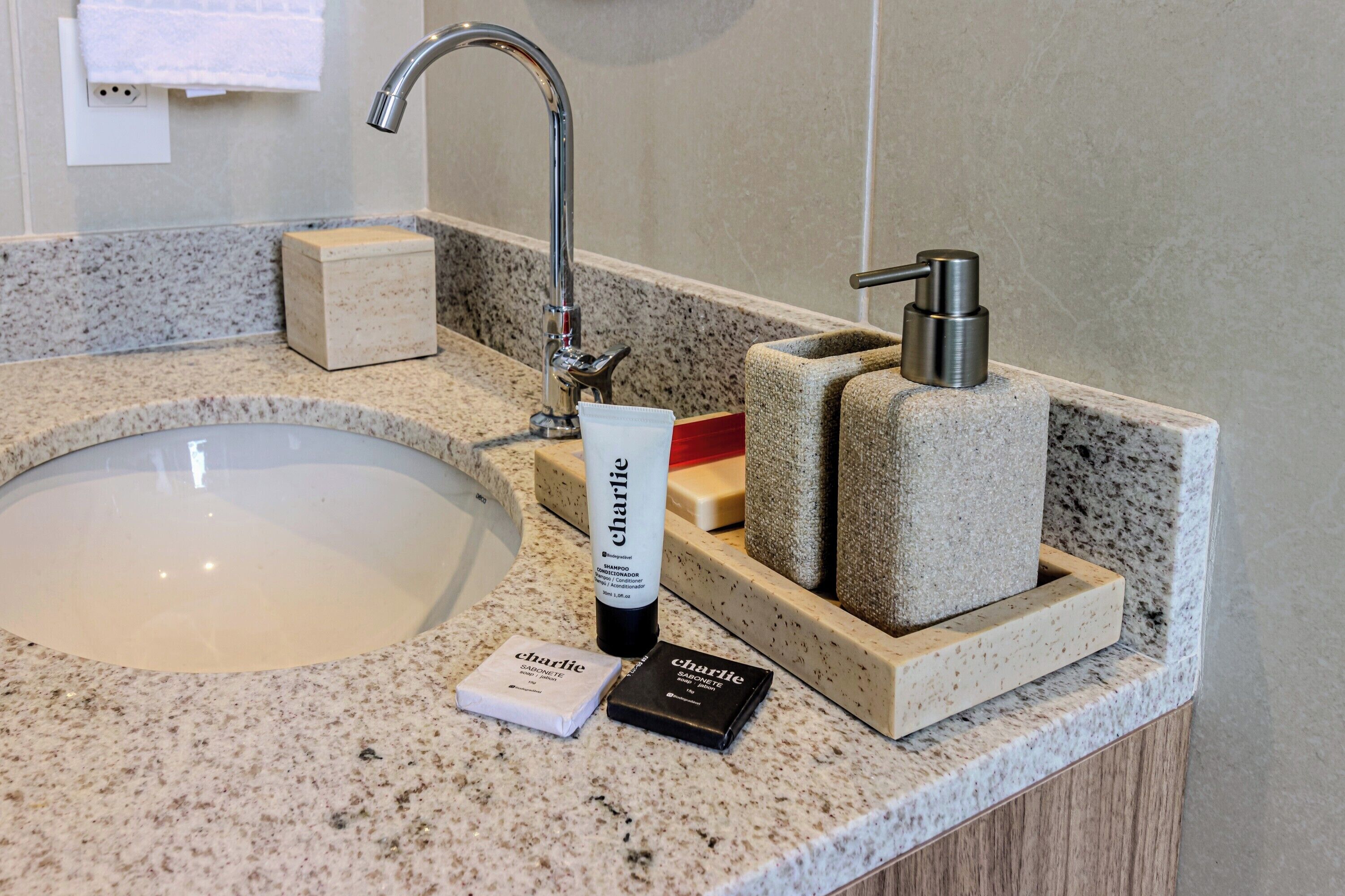 Un lavabo de salle de bain avec un plan de toilette en granit, un distributeur de savon liquide et un savon en pain.