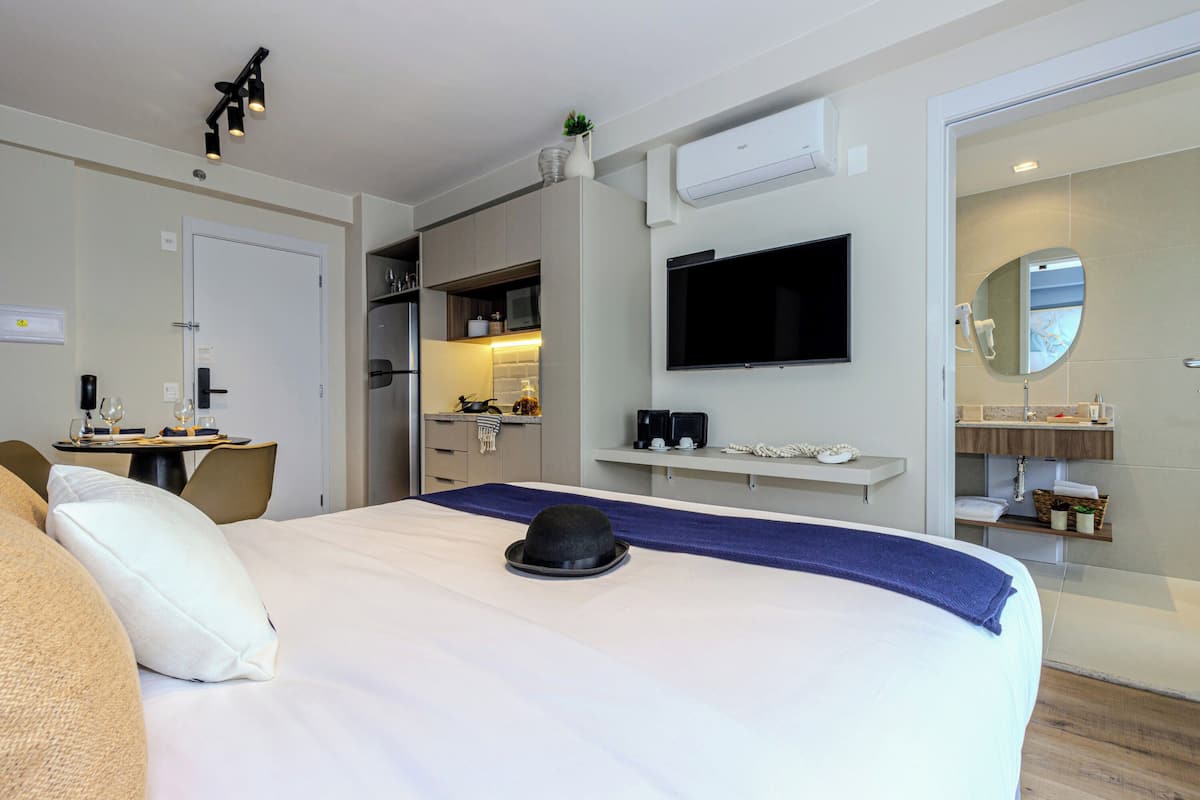 Una habitación de hotel con una cama, un escritorio, un televisor, un espejo y un baño.