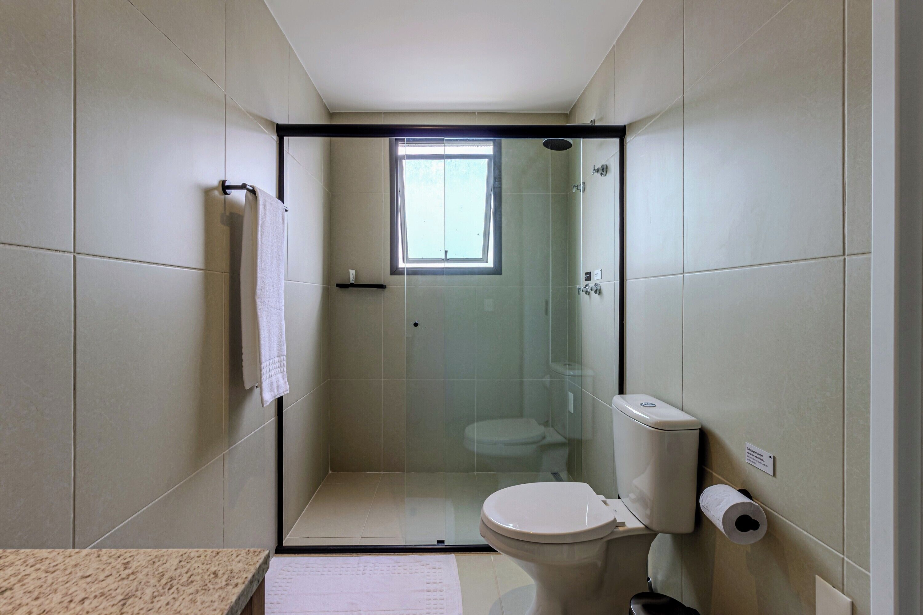 Ein kleines Badezimmer mit einer Duschkabine, Toilette und einem Papierhandtuchspender.