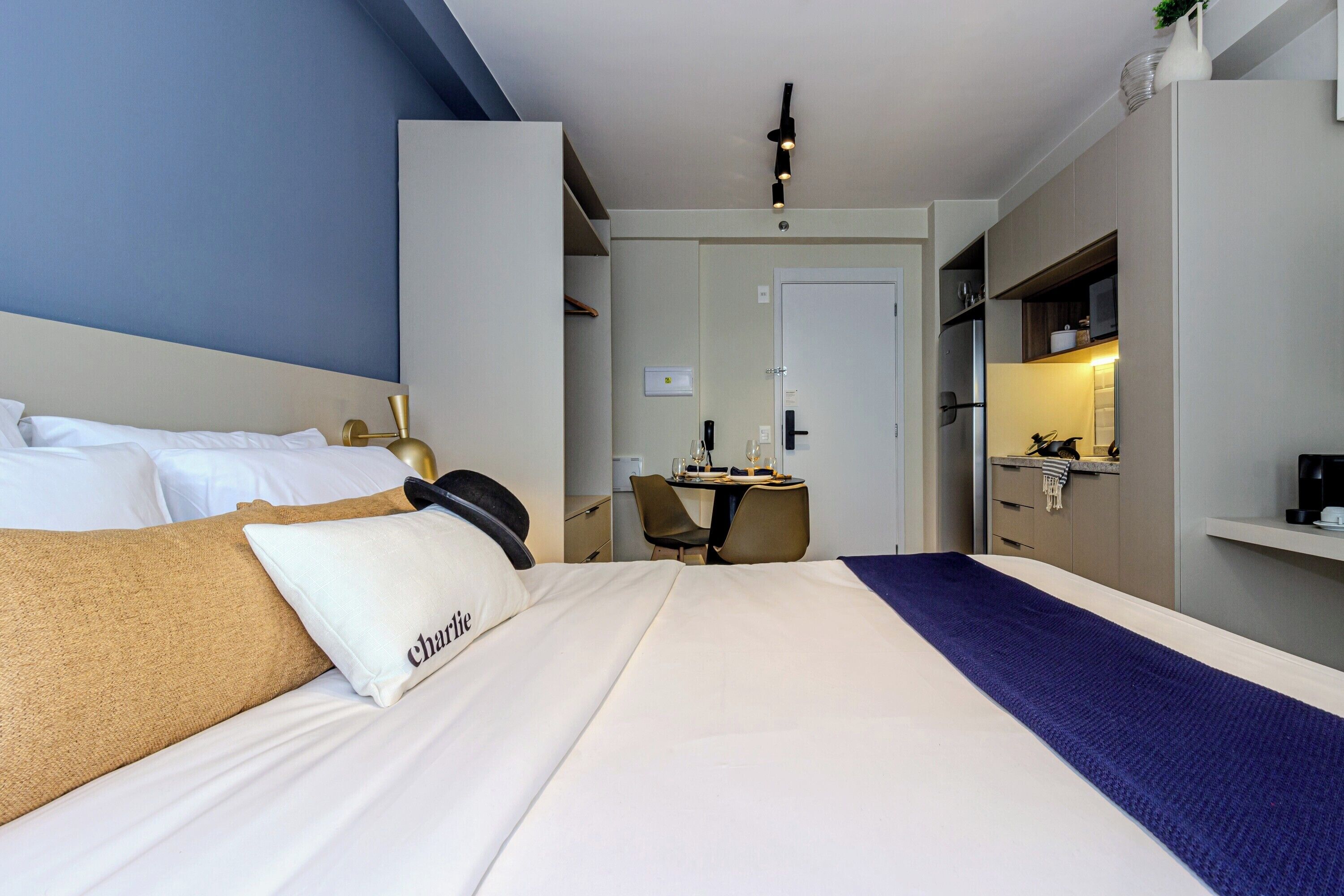 A hotel room with a bed, a desk, and a kitchenette.