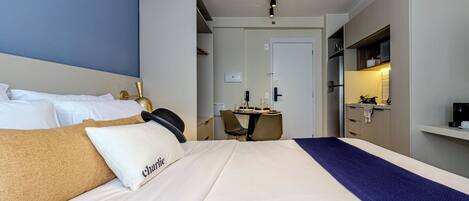 A hotel room with a bed, a desk, and a kitchenette.