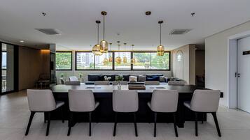 A modern dining area with a large table, six chairs, and pendant lighting.
