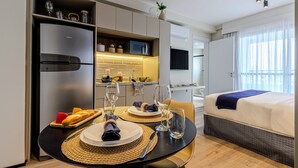 Ein modernes Hotelzimmer mit Essbereich, Küchenzeile und einem Bett.