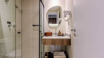 A modern bathroom with a glass shower enclosure, a wooden vanity with a mirror, and a towel rack.