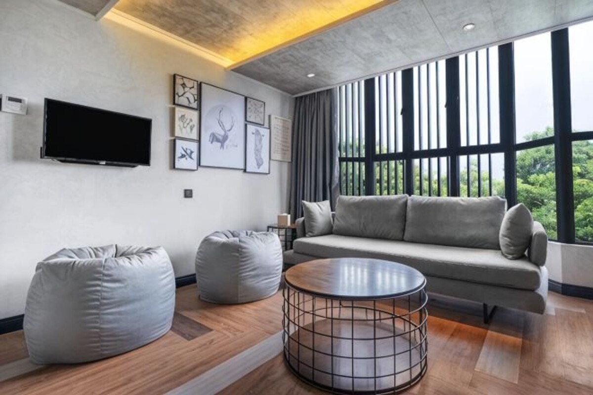 A modern living room with a sofa, two bean bags, a coffee table, and a TV mounted on the wall.