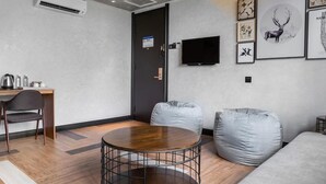 A modern room with a round wooden table, a gray sofa, and a TV mounted on the wall. - A&R Urban Hotel (Kuala Lumpur)