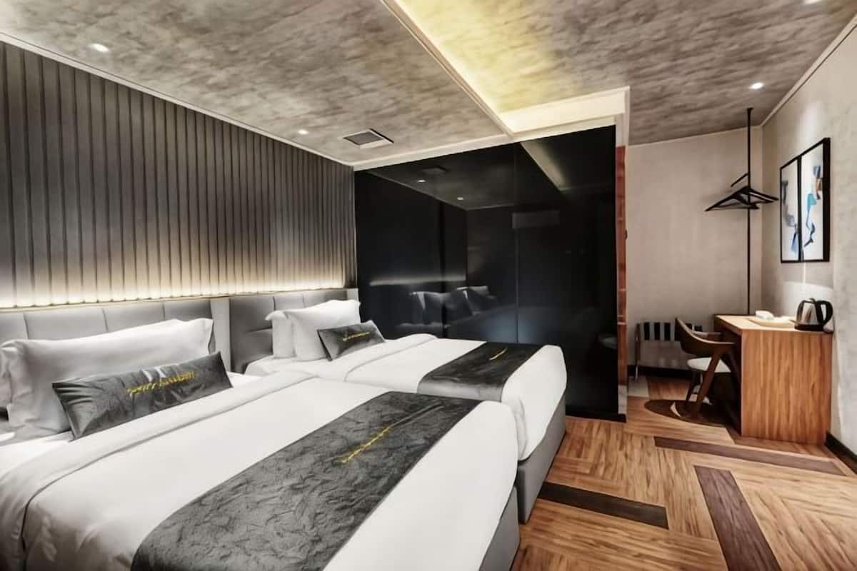 Ett modernt hotellrum med två sängar, ett skrivbord och en sittgrupp.