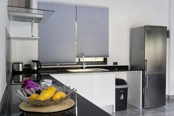 A modern kitchen with a stainless steel refrigerator, a sink, and a window with blinds. - Villa Mokkaran, 3 Bedrooms (Koh Samui)