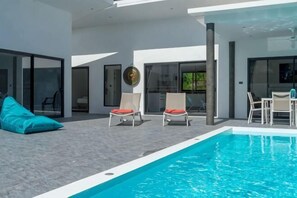 A modern outdoor pool area with a clear blue pool, two lounge chairs, and a table. - Villa Mokkaran, 3 Bedrooms (Koh Samui)