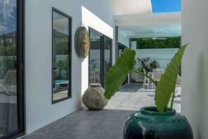 A modern interior with large windows, a green plant, and a decorative vase. - Villa Mokkaran, 3 Bedrooms (Koh Samui)
