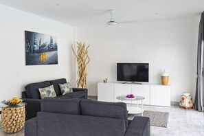 A modern living room with a sofa, a TV, a white cabinet, and a decorative vase. - Villa Mokkaran, 3 Bedrooms (Koh Samui)