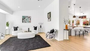 Ein modernes Wohnzimmer mit einem weißen Sofa, einem schwarzen Teppich und einem Essbereich mit Barhocker.