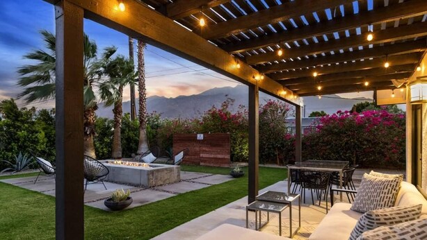 Un patio al aire libre con zona de estar cubierta, una chimenea y vistas a montañas.