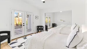 Un dormitorio con cama, ventilador de techo, una silla y una puerta que da a un patio.