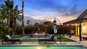 Ein Poolbereich mit Liegestühlen, einem Feuerelement und einer Pergola.