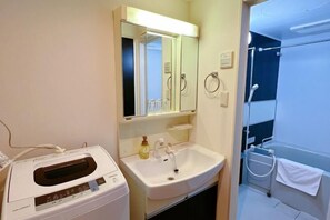 A bathroom with a white sink, a mirror, a towel rack, and a shower area. - AKATSUKI Nipponbashi(formeril Hotel Arashi Nipponbashi East No.8111) (Osaka)