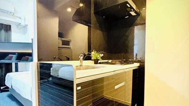 A modern hotel room with a bed, a bathroom with a sink and mirror, and a small potted plant. - Hotel Arashi Nipponbashi East No.8111 (Osaka)