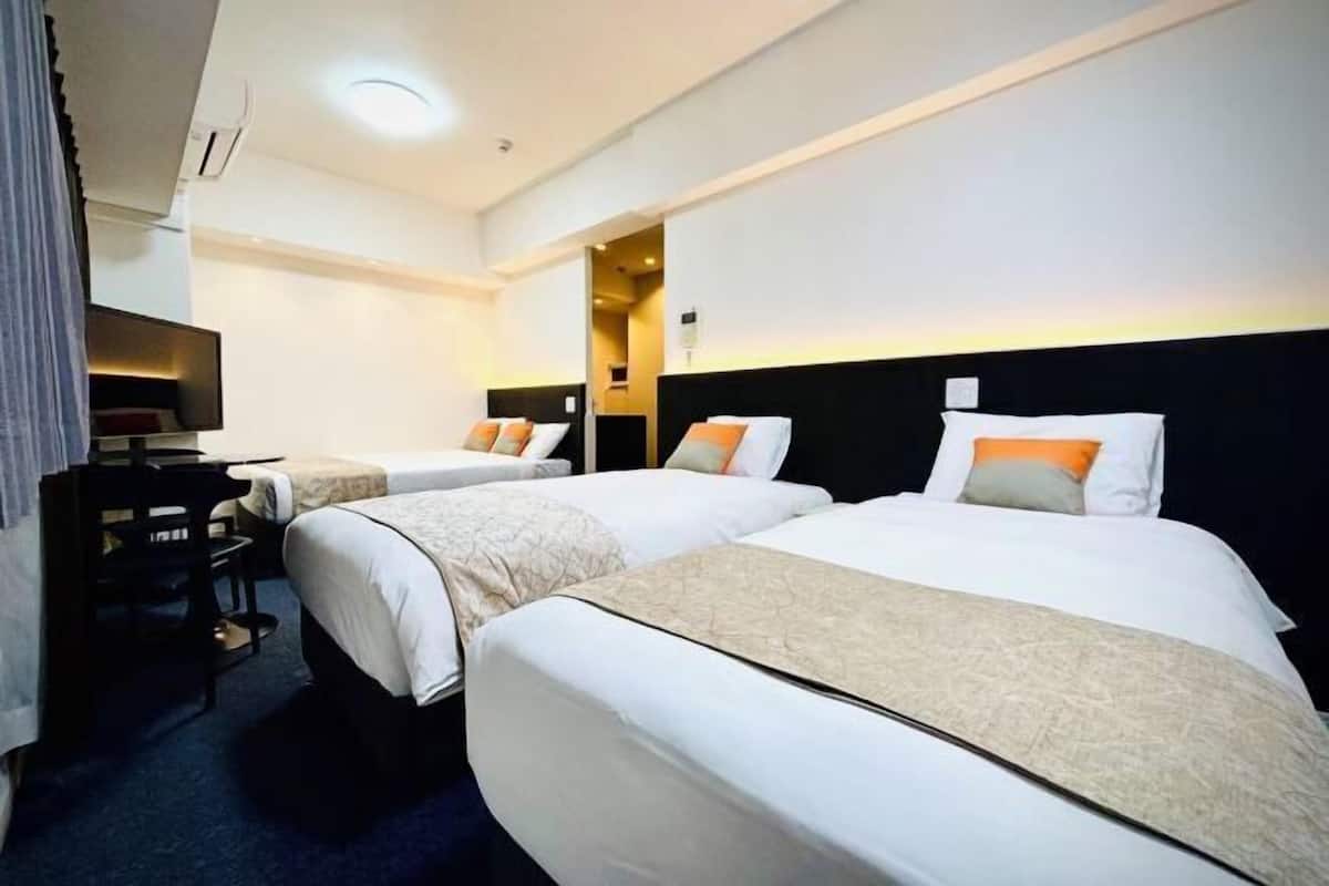 A hotel room with two beds, a desk, and a television.