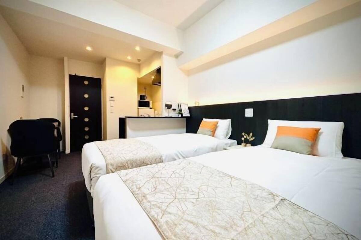 A hotel room with two beds, a desk, and a chair.