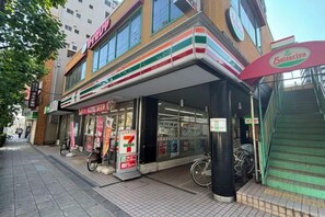 A 7-Eleven convenience store with a visible entrance, a bicycle parked outside, and a staircase leading to an upper level. - AKATSUKI Nipponbashi(formeril Hotel Arashi Nipponbashi East No.8111) (Osaka)