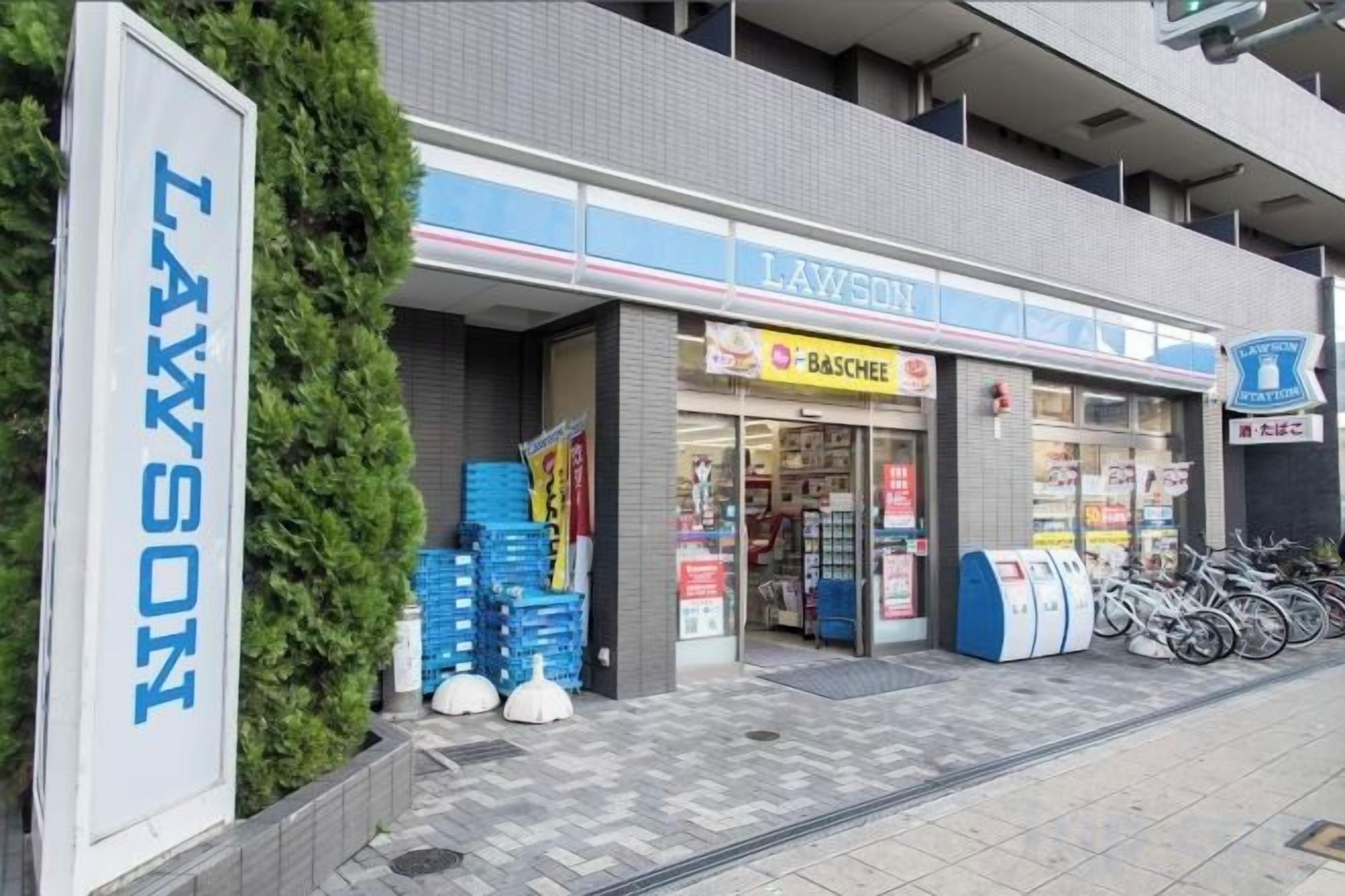 A Lawson convenience store with a visible entrance, a stack of blue crates outside, and a sign for the store.