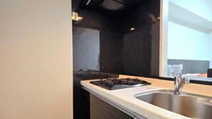 A modern kitchen with a stainless steel sink, a gas stove, and a white countertop. - Hotel Arashi Nipponbashi East No.8111 (Osaka)